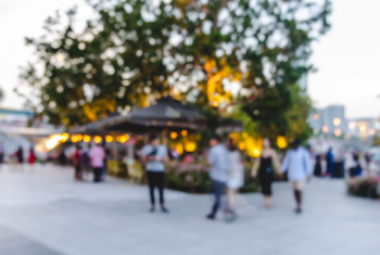 Groups of people walking around outside at a festival in a park